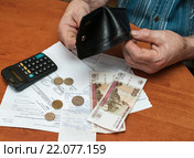 Квитанции на коммуналку. Взрослый мужчина высыпает последние деньги из кошелька на оплату коммунальных услуг (2016 год). Редакционное фото, фотограф Игорь Низов / Фотобанк Лори