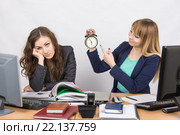 Офисные работницы в конце рабочего дня, одна с улыбкой указывает на часы, другая утомленно подпирает голову. Стоковое фото, фотограф Иванов Алексей / Фотобанк Лори