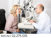 Mature optician examinating eyesight with aid of slit lamp. Стоковое фото, фотограф Яков Филимонов / Фотобанк Лори
