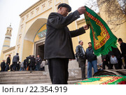 Верующий покупает молитвенный коврик (саджжaда) перед началом пятничной молитвы у входа в самую большую в Китае мечеть Ид Ках в городе Кашгаре (2016 год). Редакционное фото, фотограф Николай Винокуров / Фотобанк Лори