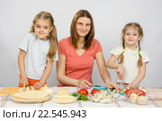 Девушка с двумя маленькими девочками за столом приготавливают ингредиенты для пиццы. Стоковое фото, фотограф Иванов Алексей / Фотобанк Лори