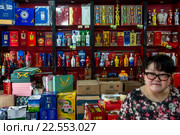 Продавец и витрина магазина в китайском городе (2016 год). Редакционное фото, фотограф Николай Винокуров / Фотобанк Лори
