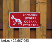 Табличка на заборе с надписью "Внимание! Добрая собака кусается" Стоковое фото, фотограф Т. З. / Фотобанк Лори