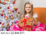 Семилетняя девочке в красивом платье подарили новогодний подарок. Стоковое фото, фотограф Иванов Алексей / Фотобанк Лори