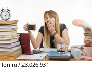 Девушка студентка занимаясь ночью зевает, держа в руках очередную чашку кофе. Стоковое фото, фотограф Иванов Алексей / Фотобанк Лори