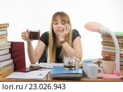 Девушка студентка грустно и сонно читает свой дипломный проект сидя с чашкой кофе в руках. Стоковое фото, фотограф Иванов Алексей / Фотобанк Лори