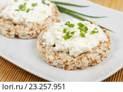 Хлебцы с творогом и порезанным кружочком луком, лежащие на белой тарелке на бамбуковой салфетке. Стоковое фото, фотограф Наталья Краснощекова / Фотобанк Лори