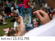 Молодой человек играет на мобильном телефоне в игру Pokemon Go от компании Niantic в Ильинском сквере города Москвы, Россия (2016 год). Редакционное фото, фотограф Николай Винокуров / Фотобанк Лори
