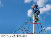 Мальчик взобрался на вершину пирамиды для лазанья на детской площадке. Стоковое фото, фотограф Pukhov K / Фотобанк Лори