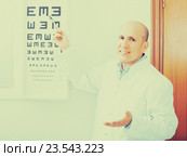 Mature optician showing symbols of Snellen chart. Стоковое фото, фотограф Яков Филимонов / Фотобанк Лори