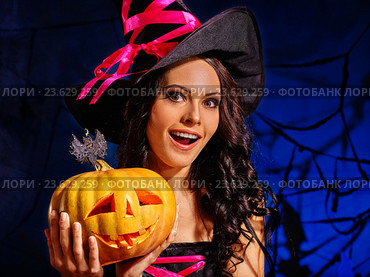 woman wearing witch hat holding big pumpkin. Стоковое фото, фотограф Gennadiy Poznyakov / Фотобанк Лори