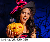 woman wearing witch hat holding big pumpkin. Стоковое фото, фотограф Gennadiy Poznyakov / Фотобанк Лори