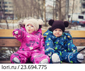 Близнецы сидят на скамейке в парке. Удивленная девочка указывает рукой на что-то. Стоковое фото, фотограф Вероника Галкина / Фотобанк Лори