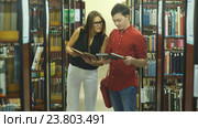 Двое студентов встречаются в библиотеке колледжа с обсуждают книги. Стоковое видео, видеограф Виктор Аллин / Фотобанк Лори