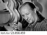 Гитарный мастер проверяет гриф гитары. luthier. Стоковое фото, фотограф Аlexander Reshetnik / Фотобанк Лори
