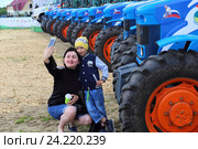 Мама с сыном фотографируются у тракторов. Чемпионат России по пахоте. Поселок Винзили, Тюменская область (2016 год). Редакционное фото, фотограф Анатолий Матвейчук / Фотобанк Лори