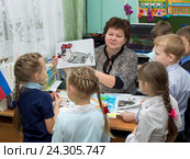 Учитель показывает детям один из рисунков, нарисованных на уроке (2015 год). Редакционное фото, фотограф Вячеслав Палес / Фотобанк Лори