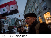 Мужчина держит флаг Сирии с портретом президента Башара Асада на митинге-шествии коммунистов в городе Москве, Россия (2016 год). Редакционное фото, фотограф Николай Винокуров / Фотобанк Лори
