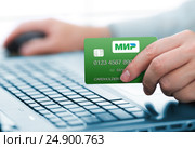 Карта национальной платежной системы "Мир" в руке пользователя компьютера (2012 год). Редакционное фото, фотограф Андрей Кузьмин / Фотобанк Лори