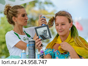 Девушке красят волосы в радужные цвета на фестивале «Das Fest - 2016» на ВДНХ. Редакционное фото, фотограф Владимир Князев / Фотобанк Лори