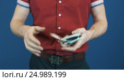 Close up magician in red shirt shuffle playing cards, show Jocker to camera. Стоковое видео, видеограф Александр Багно / Фотобанк Лори