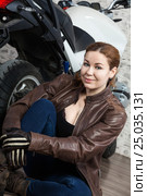 Close up portrait of young woman motorcyclist in vintage brown leather jacket sitting near a modern motorbike. Стоковое фото, фотограф Кекяляйнен Андрей / Фотобанк Лори