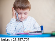 Little boy sitting at desk and talking on the phone. Стоковое фото, фотограф Happy Letters / Фотобанк Лори