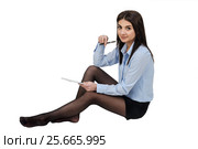 Молодая девушка, одетая в шорты и голубую рубашку, сидит на полу и делает записи в блокноте. Белый изолированный фон. Стоковое фото, фотограф Светлана Васильева / Фотобанк Лори