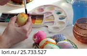 Redhead girl paints Easter eggs with a brush. on the table Easter cake, eggs, sweets, bouquet of flowers. Стоковое видео, видеограф Dmitry Chapurin / Фотобанк Лори