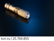 A golden flashlight on a blue surface. Стоковое фото, фотограф Alexander / Фотобанк Лори
