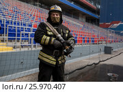 Сотрудник МЧС в полной экипировке принимает участие в учениях по тушению зажженного фанатами фальшфейера на футбольном стадионе ЦСКА в городе Москве, Россия (2017 год). Редакционное фото, фотограф Николай Винокуров / Фотобанк Лори