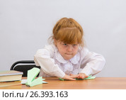 Маленькая девочка за столом старательно разглаживает бумагу на сгибе. Стоковое фото, фотограф Гетманец Инна / Фотобанк Лори