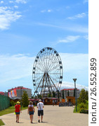 SOCHI, RUSSIA - June 18, 2017: Family goes to Ferris wheel in Sochi Park, which entered the TOP-25 of the best parks in Europe in 2016. Редакционное фото, фотограф Анна Мартынова / Фотобанк Лори