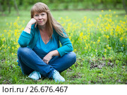 Женщина сидит на траве скрестив ноги и подперев голову рукой. Стоковое фото, фотограф Кекяляйнен Андрей / Фотобанк Лори