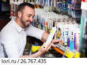 Man selecting sealant in household store. Стоковое фото, фотограф Яков Филимонов / Фотобанк Лори