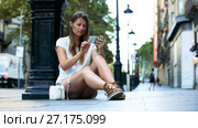 Smiling girl standing outdoors near lamp post using phone to find right address. Стоковое видео, видеограф Яков Филимонов / Фотобанк Лори