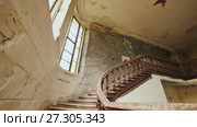 A staircase with wooden railing in an abandoned architectural building. The legacy of past architectural times. Handrail stairs made of dark wood. Shooting in motion with electronic stabilization. Стоковое видео, видеограф Mikhail Davidovich / Фотобанк Лори
