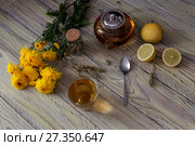 Useful herbal tea with a plant (Sideritis scardica) or Greek mountain tea with lemon in a cup and yellow chrysanthemums on a wooden table  close-up. Стоковое фото, фотограф Татьяна Ляпи / Фотобанк Лори