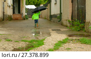 Boy with an umbrella running around the yard in rubber boots. Стоковое видео, видеограф Tatiana Kravchenko / Фотобанк Лори