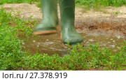 Feet in rubber boots fun to jump across the puddle. Стоковое видео, видеограф Tatiana Kravchenko / Фотобанк Лори