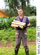 Man in overalls carrying firewood. Стоковое фото, фотограф Евгений Ткачёв / Фотобанк Лори