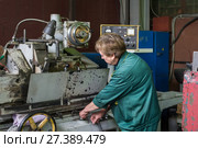 A woman works on an internal grinding machine. Stage of metal finishing of parts. (2017 год). Редакционное фото, фотограф Андрей Радченко / Фотобанк Лори