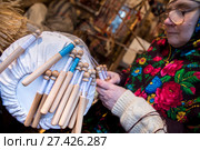 Женщина в платке с национальным русским узором плетет кружева на коклюшках на Тверской улице в центре города Москвы, Россия (2017 год). Редакционное фото, фотограф Николай Винокуров / Фотобанк Лори
