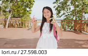 A small philippine schoolgirl shows spinning spinners. Tropical landscape. Summer. Childhood. Стоковое видео, видеограф Mikhail Davidovich / Фотобанк Лори