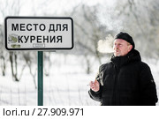 Мужчина курит сигарету возле таблички "Место для курения" Стоковое фото, фотограф Игорь Низов / Фотобанк Лори