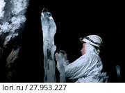 Speleologist takes a sample of the ice structure on the background of a darkness and rocky wall covered with large crystals of hoarfrost. Стоковое фото, фотограф Евгений Харитонов / Фотобанк Лори