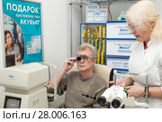Woman optometrist checks vision of a man. Selection of glasses with diopters for glasses with an optometric frame (2018 год). Редакционное фото, фотограф Юлия Бабкина / Фотобанк Лори