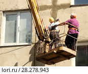 Женщины рабочие штукатуры ремонтируют фасад дома пятиэтажки — подъемный кран автовышка с корзиной люлькой летом на фоне стены. Стоковое фото, фотограф Илья Илмарин / Фотобанк Лори
