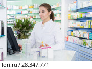 Young pharmacist is standing near cashbox. Стоковое фото, фотограф Яков Филимонов / Фотобанк Лори