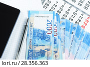 Несколько новых российских двухтысячных купюр, календарь, блокнот и смартфон на столе. Стоковое фото, фотограф Наталья Гармашева / Фотобанк Лори